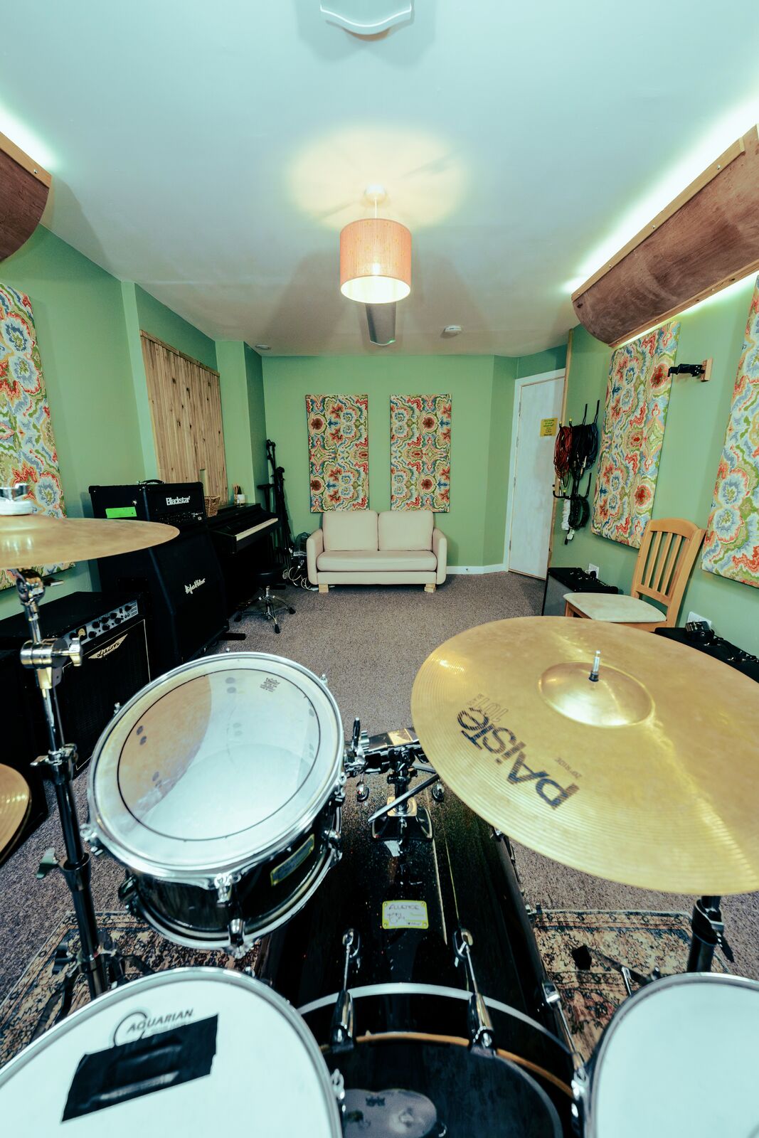 View across the Live Room from the drum kit, showing amplifiers, piano and seating